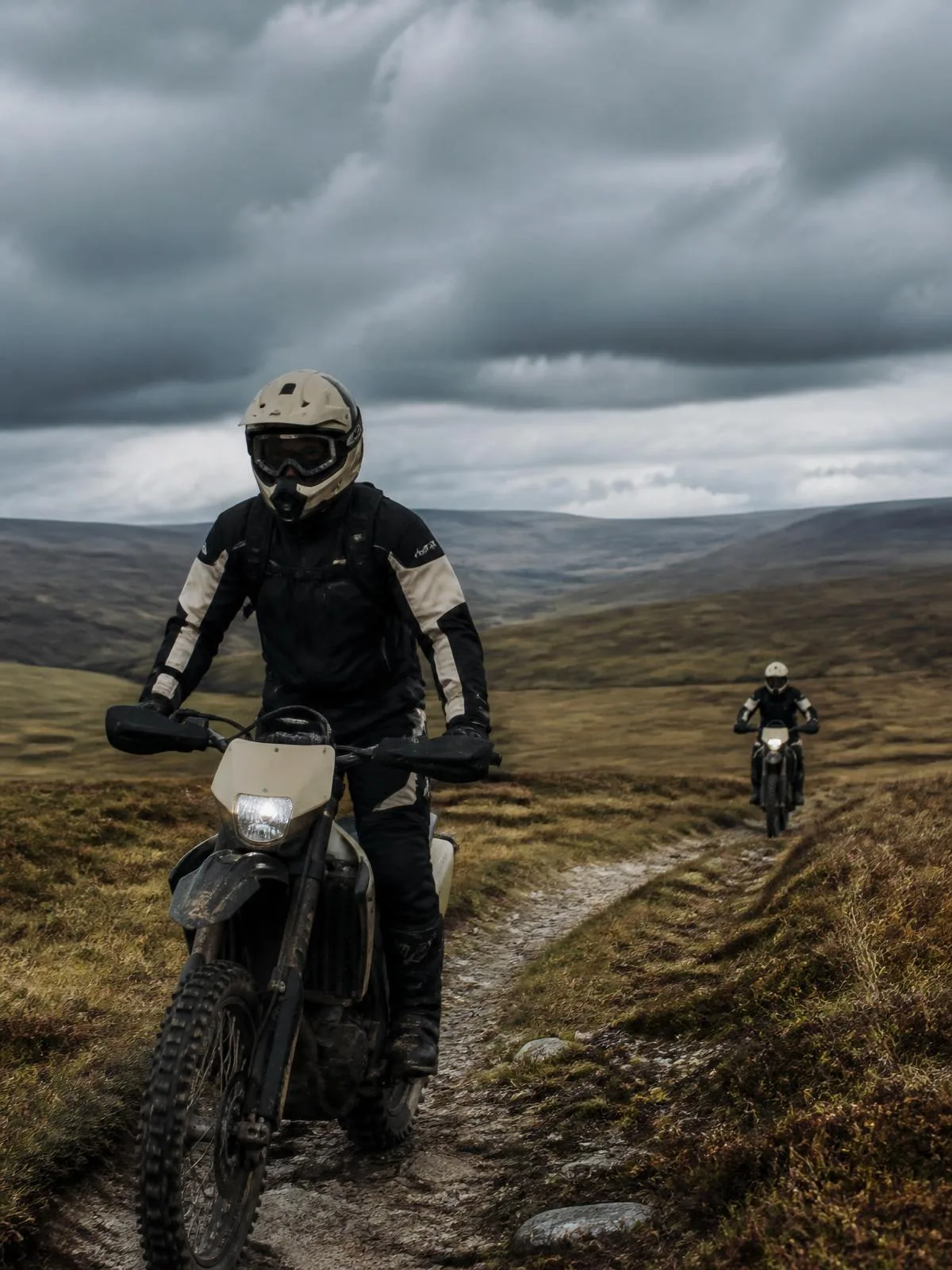 Two enduro riders crossing open moorland